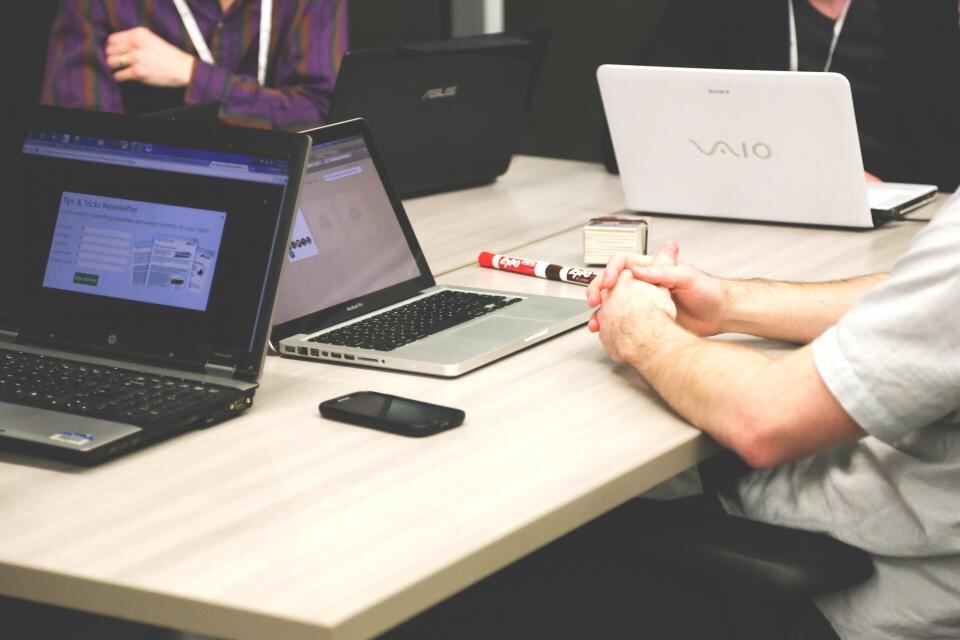 Several laptops open side by side on a long desk